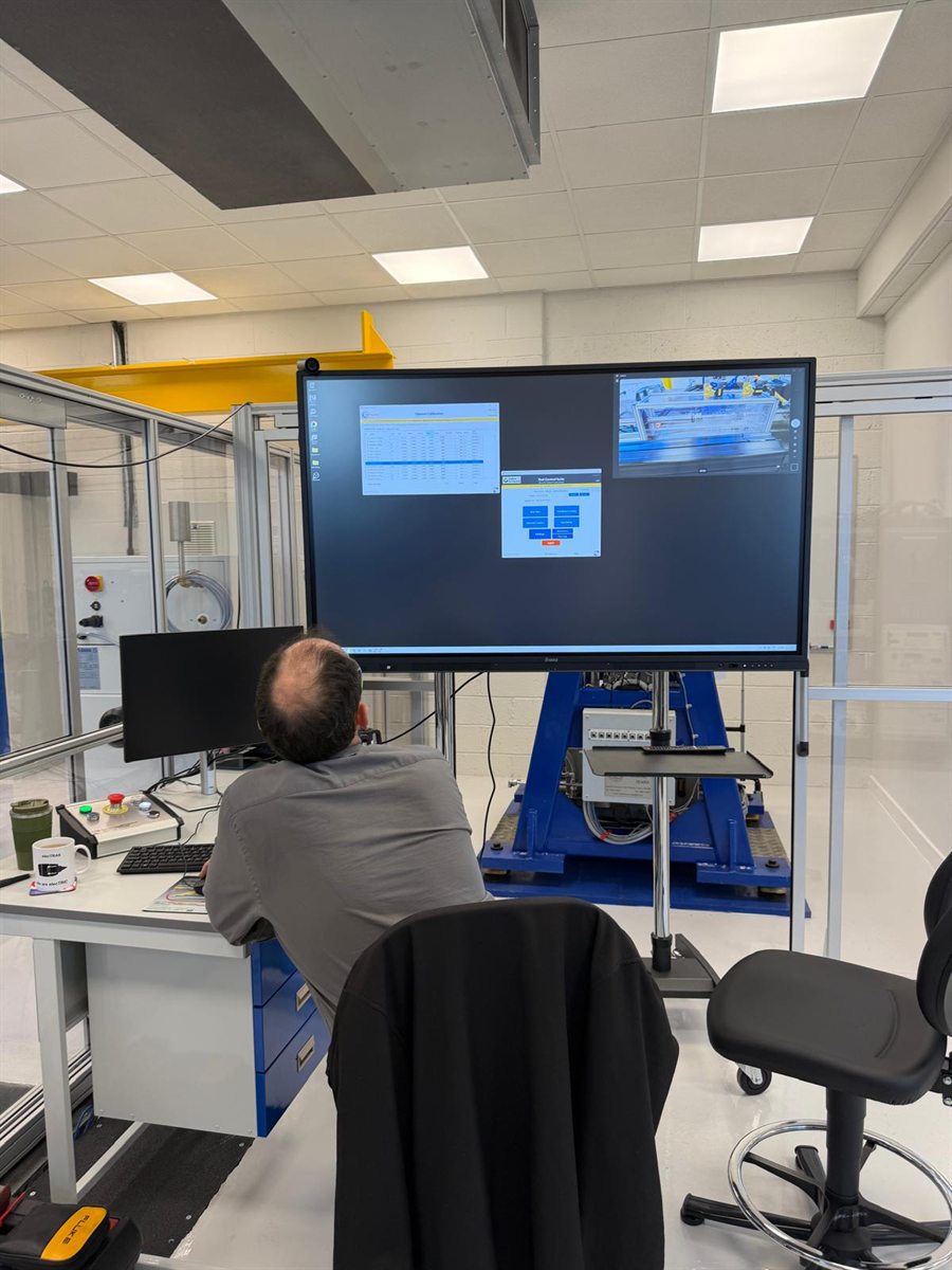 A CCS engineer operating the CCMachina software on the large test-cell display, with the rig behind